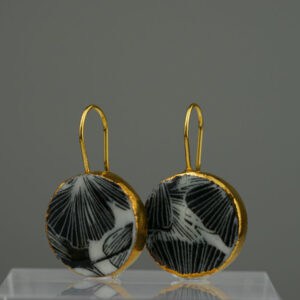 Diese handgefertigte Ohrringe aus Porzellan kombinieren das kontrastreiche Schwarz-Weiß eines Ginkgo-Motivs mit einem edlen Rahmen aus 24-karätigem Gold.