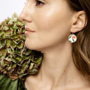 Eine tiefrote, getupfte Rose mit zarten grünen Blättern, als wäre sie gerade frisch gepflückt. Sie verkörpert Eleganz und die zeitlose Schönheit klassischer Blumenmalerei.